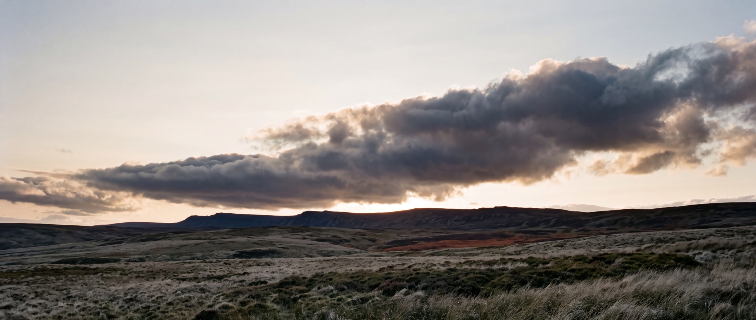 Cloud moving over an open moorland ridge under a wide sky.
