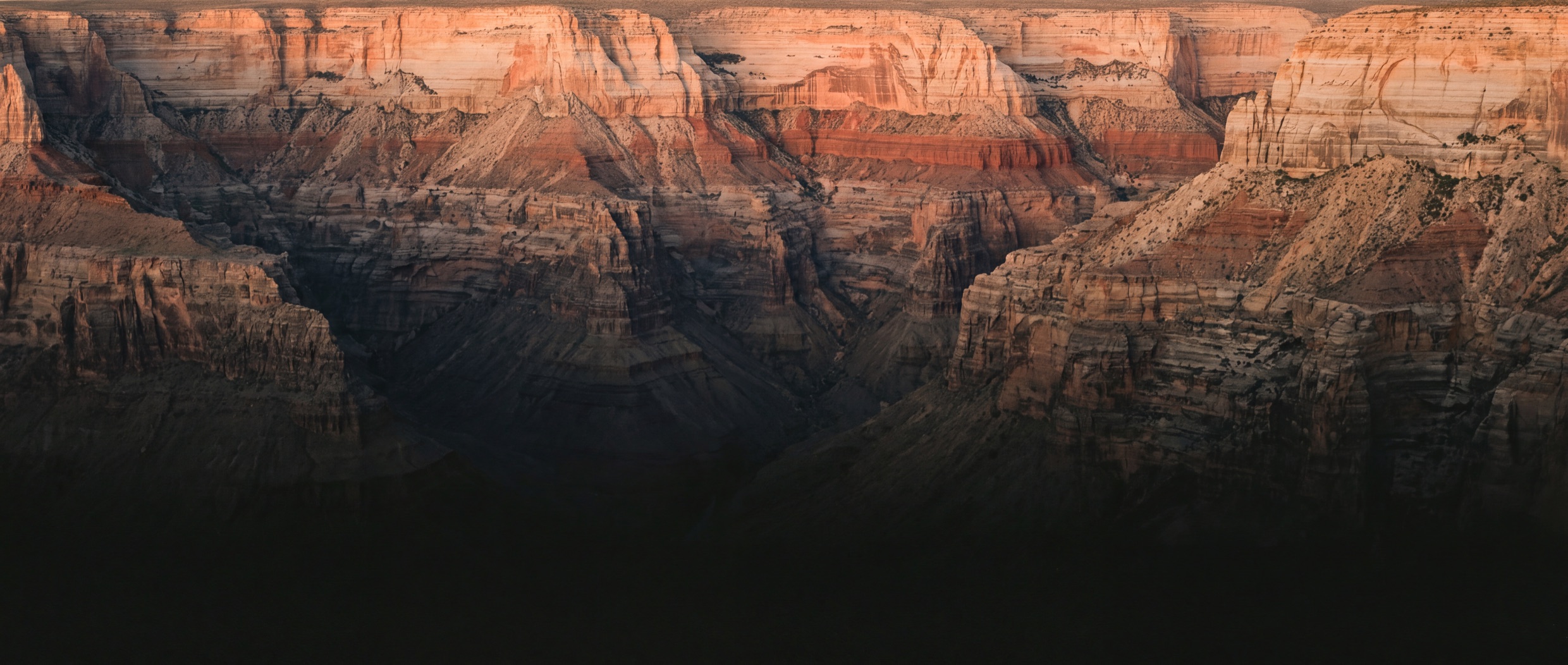 Canyon walls at last light, warm glow above and cool shadow below.
