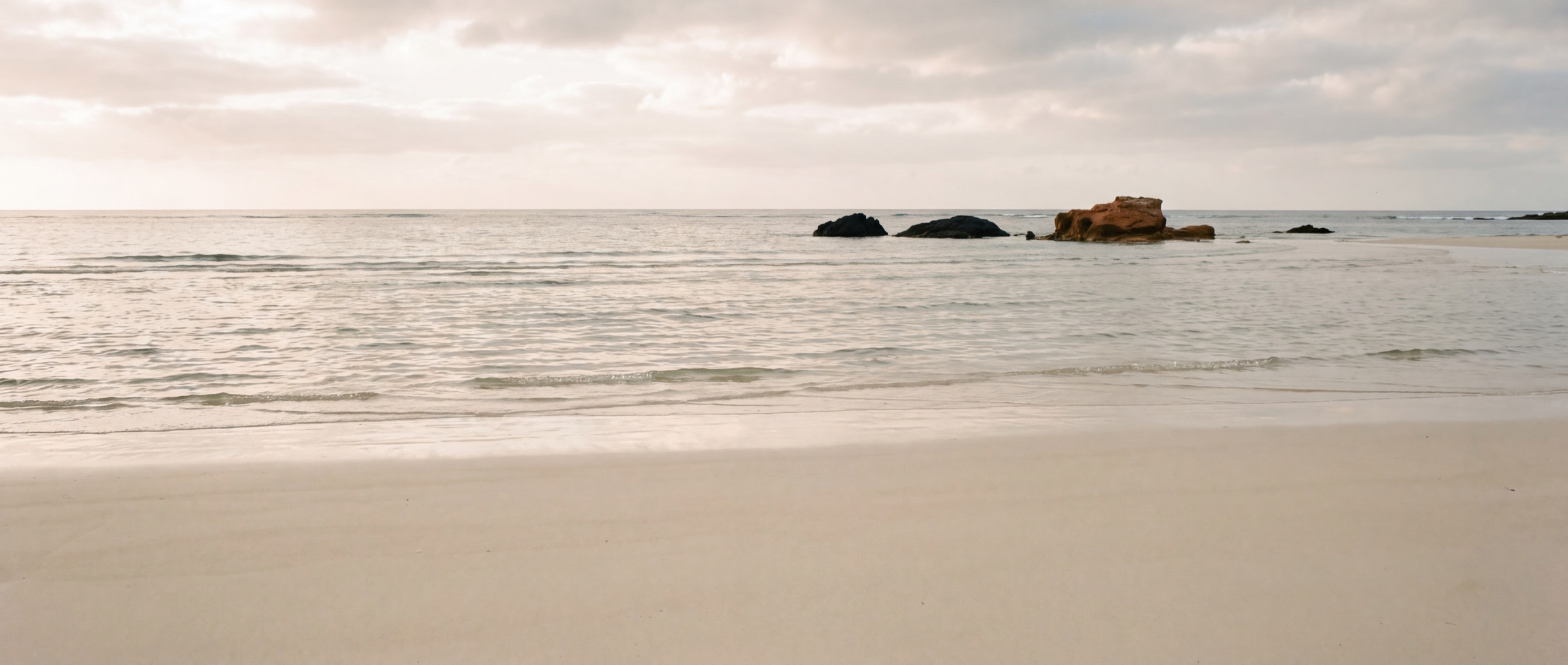 Shallow water over pale sand on an open coast in late afternoon light.