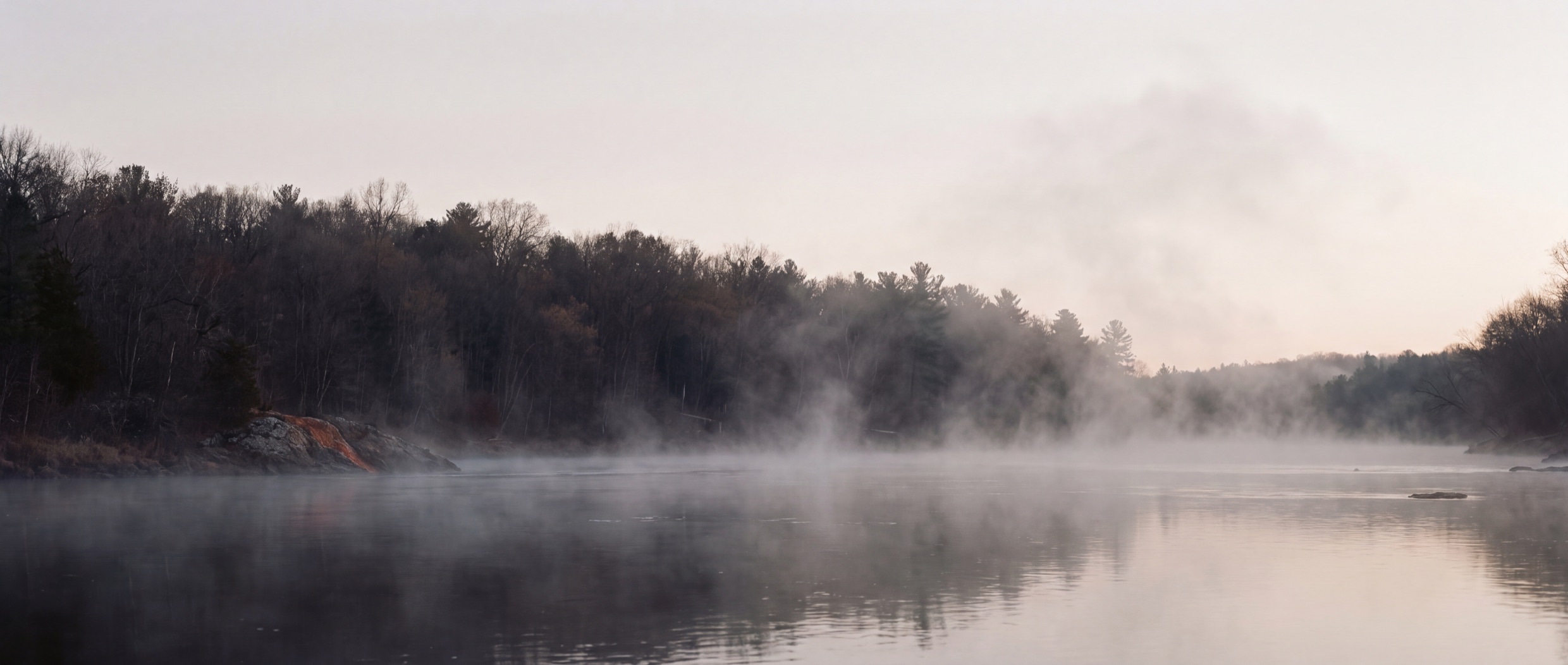 Mist lifting off a slow river at first light.